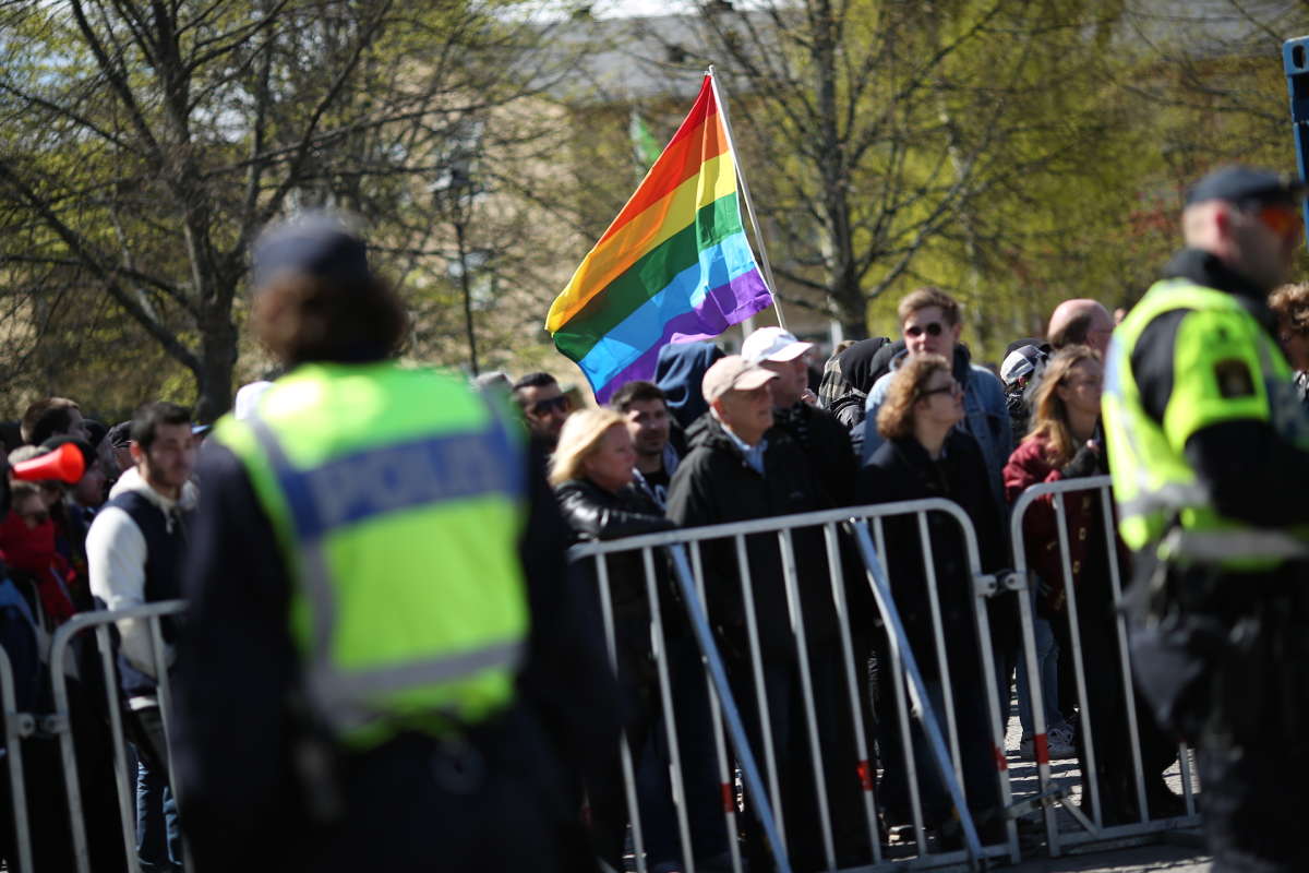 En pride-flagga syns bland motdemonstranterna. En pride-flagga syns bland motdemonstranterna.